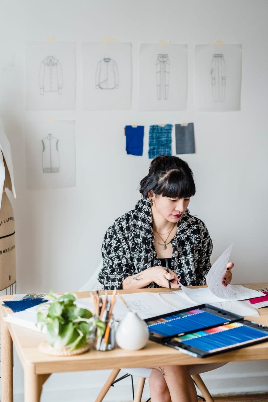 A young designer reviewing printed work in her studio