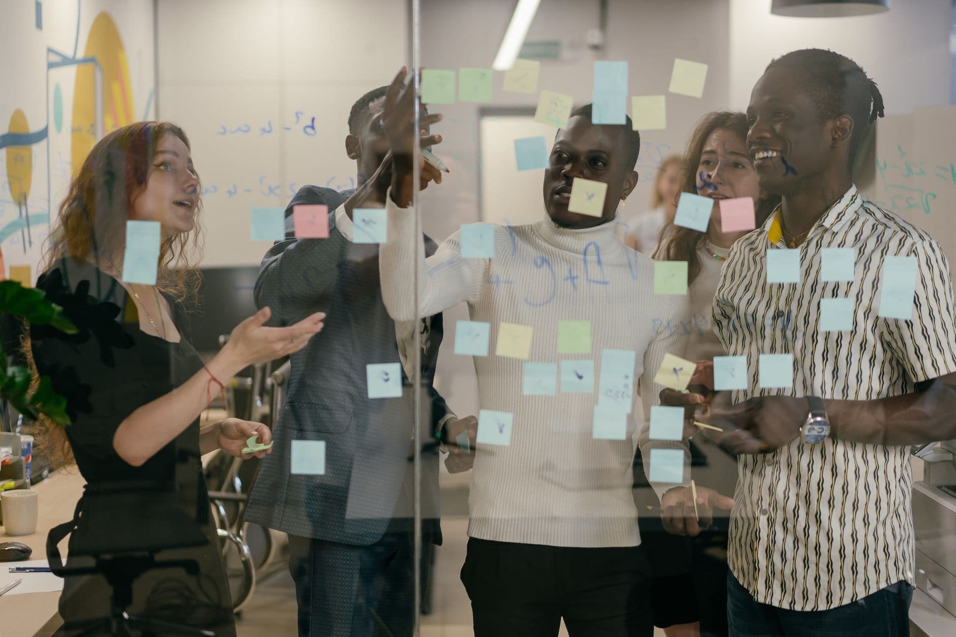 A team working through a project plan on a glass wall of sticky notes