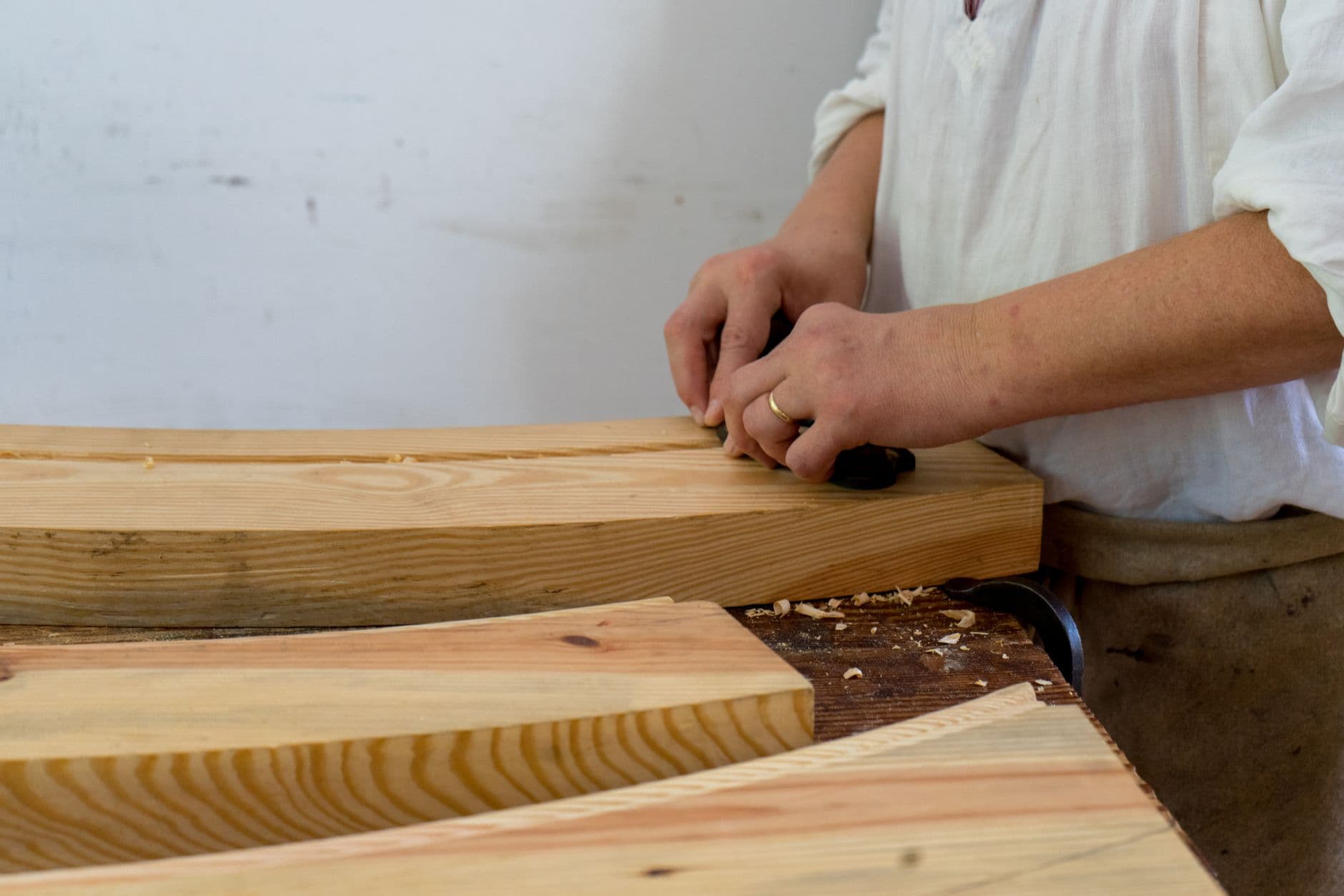 Hands shaping timber at a workshop bench
